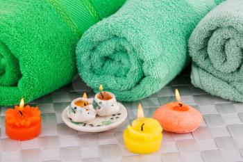Spa set with towels and candles on bamboo background.
