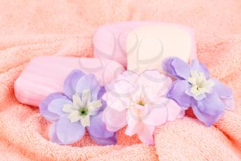 Colorful soaps and flowers on towel.