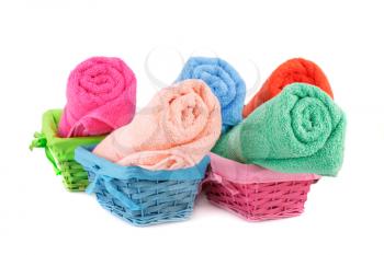 Rolled colorful towels in bamboo baskets isolated on white background.