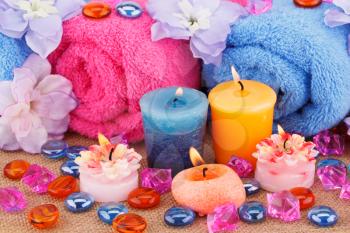 Spa set with towels, candles, stones and flowers on canvas background.
