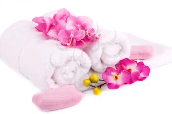 White rolled towels with soaps and flowers on white background.