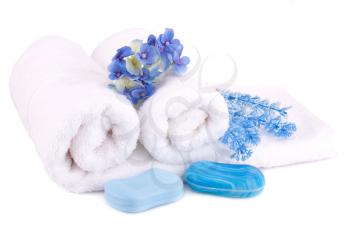 White rolled towels with soaps and flowers isolated on white background.