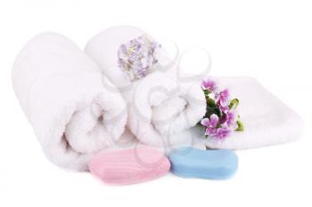 White rolled towels with soaps and flowers isolated on white background.