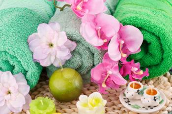 Spa set with towels, candles and flowers on colorful bamboo background.