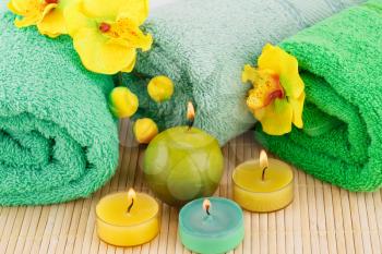 Spa set with towels, candles and flowers on bamboo background.
