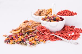 Dried fruits, berries and seeds in bowls on gray background.