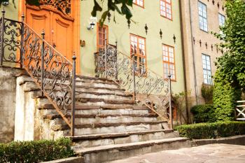 Old buiding entrance with metallic handrails and wooden door in Oslo, Norway.