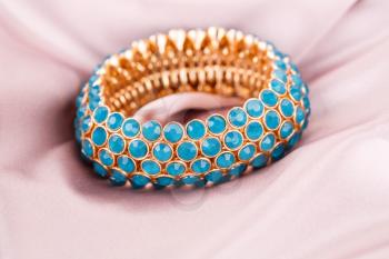 Stylish bracelet with blue stones on fabric background.
