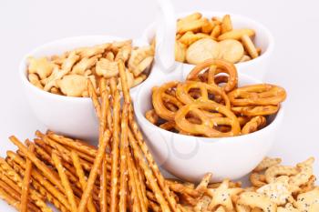 Different salted crackers in bowl on white background.
