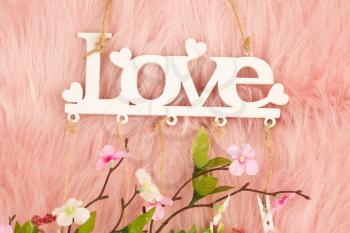 White wooden word love and flowers on pink fur background.