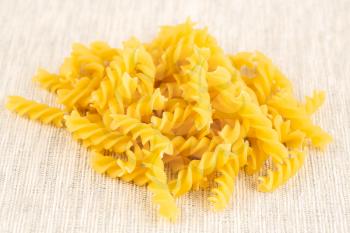 The heap of fusilli pasta on the fabric background.