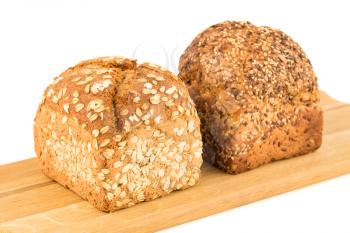 Wholegrain bread buns with seeds and oat on wooden board on white background.