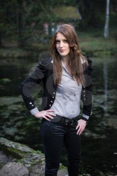 young woman in jacket standing and posing at the lake