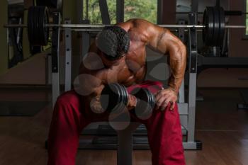 shirtless bodybuilder doing heavy weight exercise for biceps