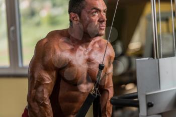 bodybuilder doing heavy weight exercise for triceps with cable