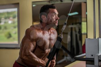 bodybuilder doing heavy weight exercise for triceps with cable