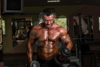 bodybuilder doing heavy weight exercise for biceps with dumbbell