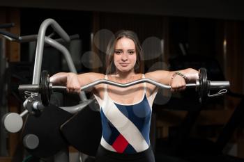 Young Woman Doing Heavy Weight Exercise For Trapezius