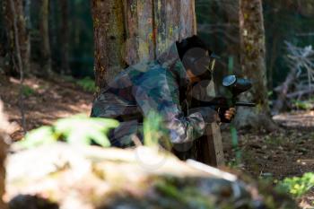 Paintball Players Hide Behind Tree