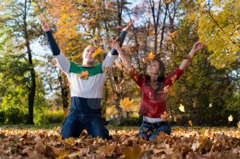 Young Couple Throwing Fall Leaves