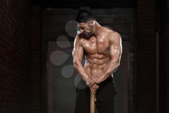 Portrait Of A Physically Fit Man Showing His Well Trained Body And Holding A Hammer