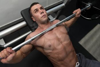 Young Man In Gym Exercising Chest On The Bench Press