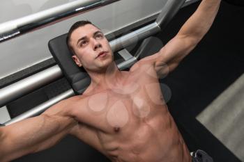 Young Man In Gym Exercising Chest On The Bench Press