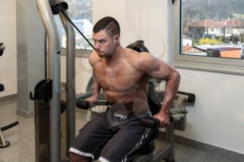 Young Physically Bodybuilder Working Out Triceps On Machine