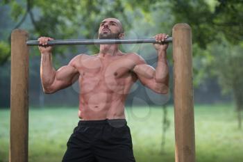 Muscular Built Young Athlete Working Out In An Outdoor Gym - Doing Chin-Ups