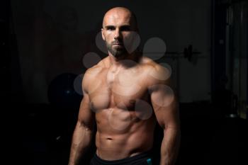 Portrait Of A Physically Fit Man Showing His Well Trained Body In A Dark Room