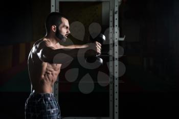Young Man Working Out Shoulders In A Dark Gym - Bodybuilder Doing Heavy Weight Exercise For Shoulder