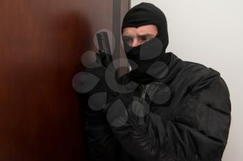 Man With A Black Mask And Gun Is Breaking Into A Home - Standing Behind The Door
