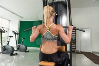 Young Fitness Woman Working Out Back On Machine In Fitness Center