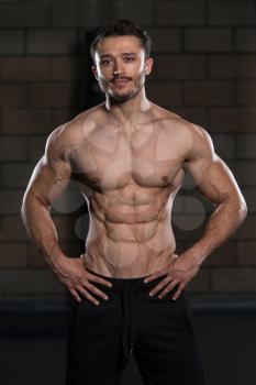 Handsome Man Standing Strong In The Gym And Flexing Muscles - Muscular Athletic Bodybuilder Fitness Model Posing After Exercises