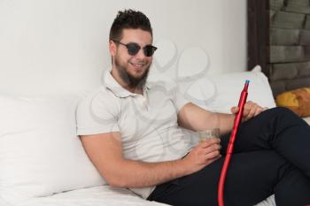 Young Man Smoking Shisha At Arabic Restaurant - Man Exhaling Smoke Inhaling From A Hookah