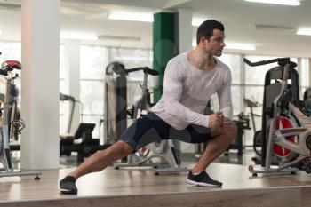 Muscular Man Stretches At The Floor In A Gym And Flexing Muscles - Muscular Athletic Bodybuilder Fitness Model