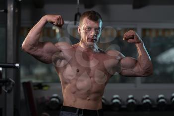 Healthy Man Standing Strong In The Gym And Flexing Muscles - Muscular Athletic Bodybuilder Fitness Model Posing After Exercises