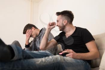 Two Young Brothers Having Happy Time Together Playing Video Games At Home