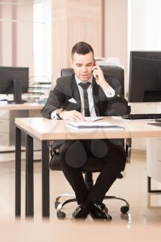 Young Handsome Businessman Working With Computer At Desk In The Modern Office Talking On Phone