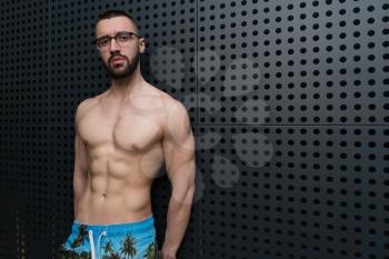 Portrait of a Young Physically Fit Man Showing His Well Trained Body - Muscular Athletic Bodybuilder Fitness Model Posing After Exercises on Wall Near the Wall - a Place for Your Text