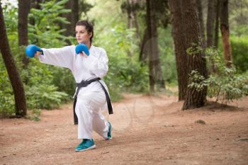 Young Woman Practicing Her Karate Moves in Wooded Forest Area - White Kimono - Black Belt