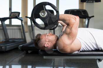 Muscular Man Doing Heavy Weight Exercise For Triceps With Barbell In Gym