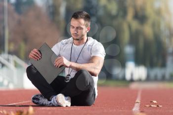 Personal Trainer In Sports Outfit Takes Notes On Clipboard in City Park Area - Training and Exercising for Endurance - Healthy Lifestyle Concept Outdoor