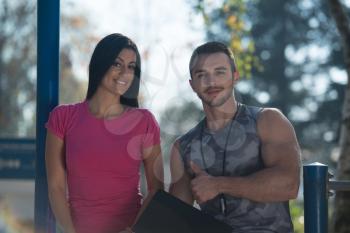 Personal Trainer Takes Notes While Young Woman Exercise in City Park Area - Training and Exercising for Endurance - Healthy Lifestyle Concept Outdoor