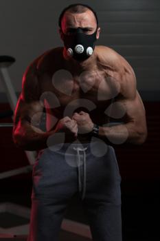 Healthy Young Man Standing Strong  In Elevation Mask And Flexing Muscles - Muscular Athletic Bodybuilder Fitness Model Posing After Exercises