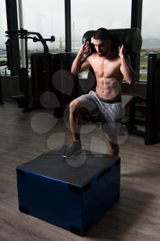 Fit Young Man Doing Box Jumping At A Style Gym - Male Athlete Is Performing Box Jumps At Gym With Weights