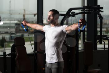 Muscular Fitness Bodybuilder Doing Heavy Weight Exercise For Shoulders With Pull Rope Elastic Cable In The Gym