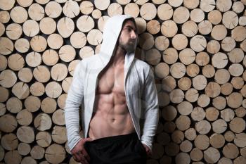 Portrait of a Young Physically Fit Man Showing His Well Trained Body In Hoodie - Muscular Athletic Bodybuilder Fitness Model Posing After Exercises on Wall Near the Wall - a Place for Your Text
