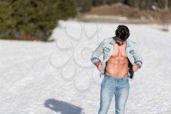 Healthy Young Man Standing Strong Flexing Muscles While Wearing Blue Jeans - Muscular Athletic Bodybuilder Fitness Model Posing Outdoors - a Place for Your Text