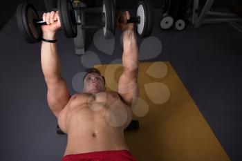 Strong Man In The Gym And Exercising Chest With Dumbbells - Muscular Athletic Bodybuilder Fitness Model Exercise